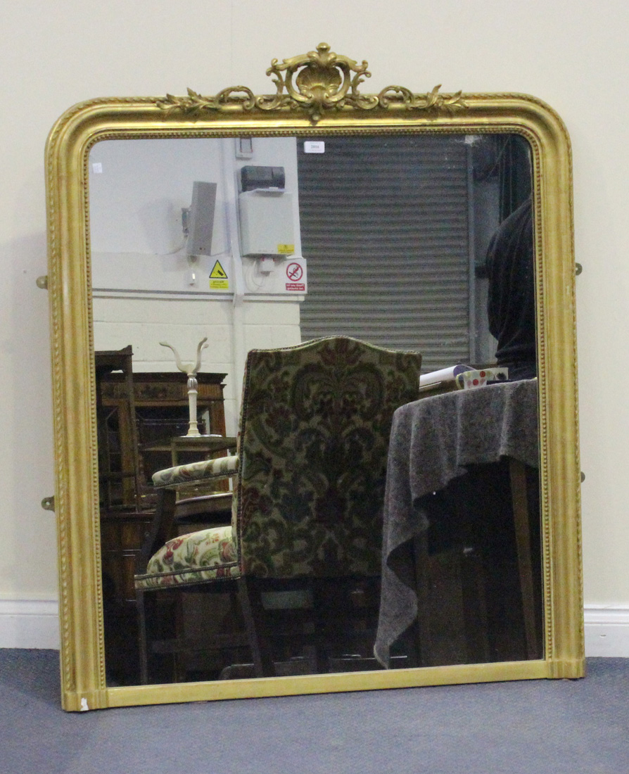 A late 19th/early 20th Century gilt composition overmantel mirror with a shell and scroll