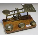 A Victorian set of postal scales and weights on an oak pedestal base, width approx 25.4cm (faults).