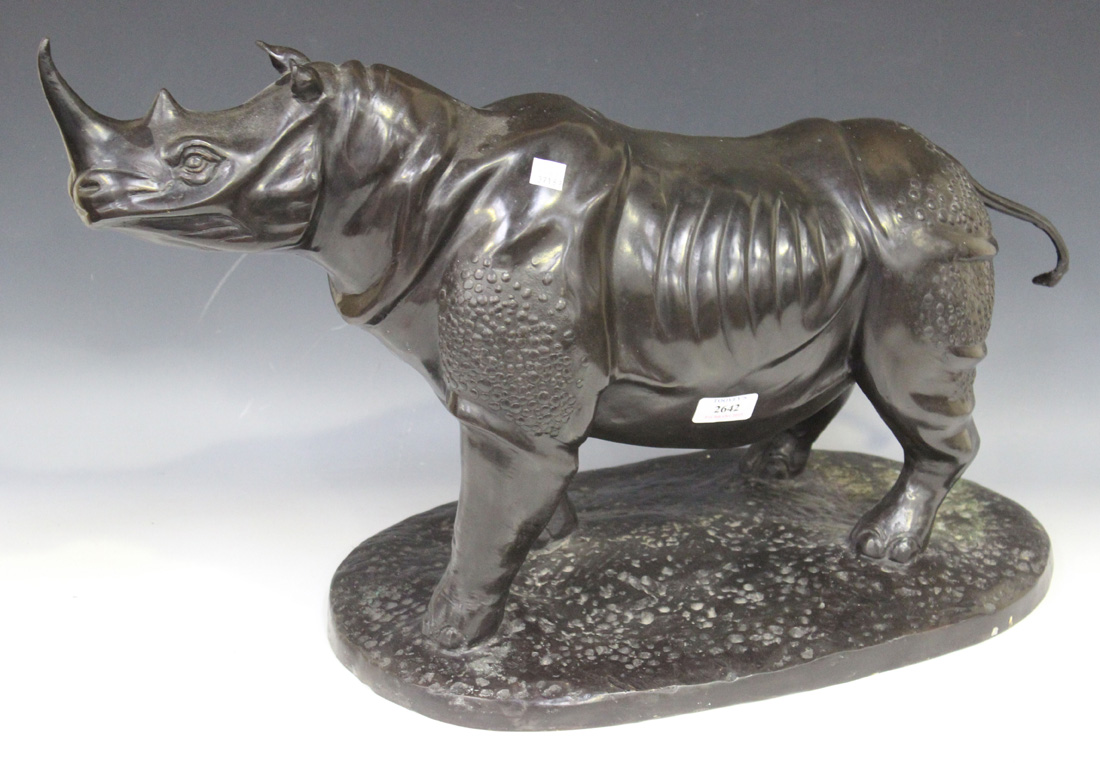 A 20th Century black patinated cast bronze figure of a rhinoceros, standing on an oval base,