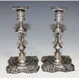 A pair of Edwardian silver tapersticks, each with a detachable square nozzle above a baluster stem