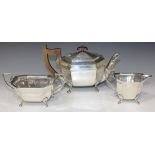 A silver three piece tea set of rectangular form with canted corners, raised on paw feet, comprising