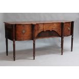 A George III figured mahogany and rosewood crossbanded sideboard, the shaped top with four