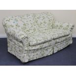 An early 20th Century three seat settee covered in floral loose covers, on bun feet and castors,