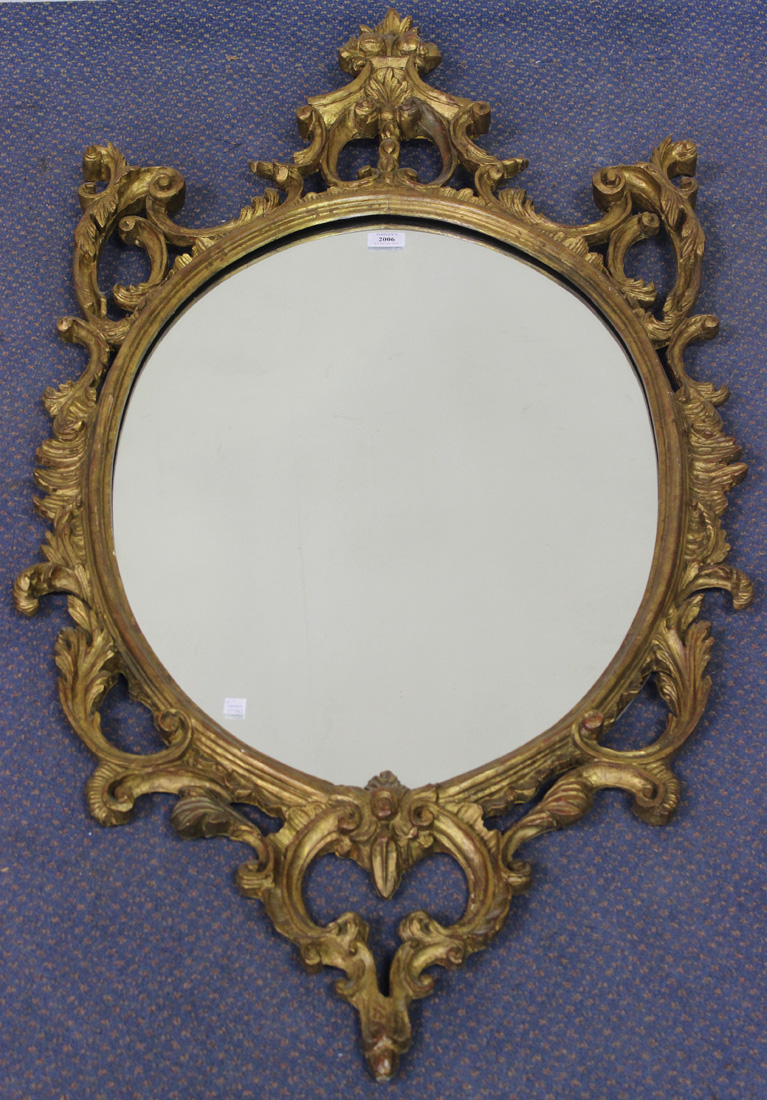 A 20th Century Italianate oval giltwood wall mirror with a carved scrollwork frame, approx 129cm x