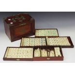 A Chinese mah jong set, 20th Century, with bone and bamboo tiles, within a brass mounted hardwood