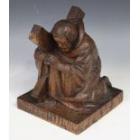 A 20th Century carved oak figure of St Andrew, praying on one knee and supporting an X-shaped cross,