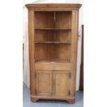 A George III pine corner cabinet, the moulded pediment above open shelves, the base fitted with a