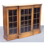 A George V oak breakfront bookcase, the moulded top above three astragal glazed doors, on a plinth