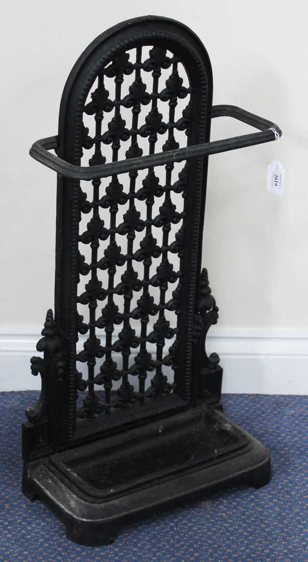 A Victorian style black painted cast iron stickstand, the pierced panel back above a drip pan,