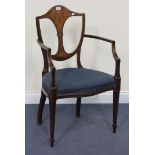 An Edwardian mahogany elbow chair, the shield back profusely inlaid with foliate scrolls, on