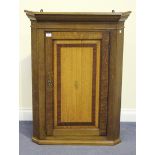A George III oak and mahogany crossbanded corner cupboard, the panelled door inlaid with a central