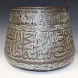 An Islamic brass jardinière, late 19th Century, the body decorated in relief with a continuous