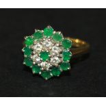 A gold, emerald and diamond hexagonal cluster ring, claw set with a circular cut emerald in a