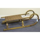 An early 20th Century German ash sledge with woven strap seat, length approx 113cm.