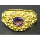 A gilt metal and mauve paste set oval hinged bangle in a cannetille work design to the centre, the