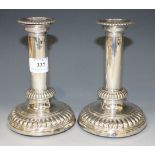 A pair of George III silver candlesticks with detachable nozzles above cylindrical stems and