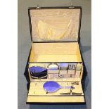 A leather vanity case fitted with silver and blue enamelled dressing table items, comprising hand