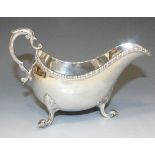 A George III Irish silver sauce boat with foliate capped scroll handle above a gadrooned rim, raised