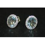 A pair of 18ct white gold, aquamarine and diamond earstuds, each with an oval cut aquamarine
