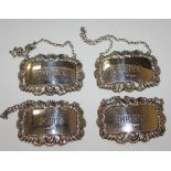 A set of four silver decanter labels of rectangular form with scroll rims, comprising 'Whiskey', '
