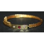 A 15ct gold, ruby and diamond three stone hinged bangle, the front mounted with a cushion shaped