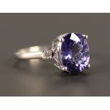 An 18ct white gold tanzanite and diamond three stone ring, claw set with the oval cut tanzanite