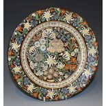 A Swiss Thoune pottery plate, late 19th Century, enamelled with flowers on a brown glazed ground,