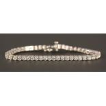A 14ct white gold and diamond line bracelet, claw set with a row of circular cut diamonds, on a snap