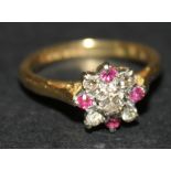 An 18ct gold diamond and ruby nine stone cluster ring, claw set with the principal circular cut