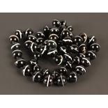 A single row necklace of fifty-nine graduated spherical banded agate beads on a matching spherical