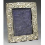 An Edwardian silver rectangular photograph frame, decorated in relief with scrolling tendrils,