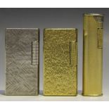 Two gold plated pocket lighters by Dunhill and a nickel plated pocket lighter by Dunhill.