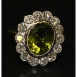 A gold, peridot and diamond oval cluster ring, collet set with the oval cut peridot in a surround of