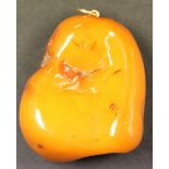 A mottled opaque butterscotch coloured amber pendant of irregular form, gross weight approx 23.7g,