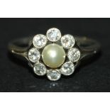 A diamond and cultured pearl cluster ring, mounted with the single cultured pearl in a surround of