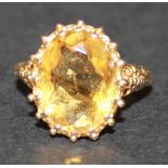A 9ct gold ring, claw set with an oval cut citrine between decorated shoulders, ring size approx K.