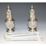 A pair of Edwardian silver pepper casters, each with a domed pierced cover and knop finial above a