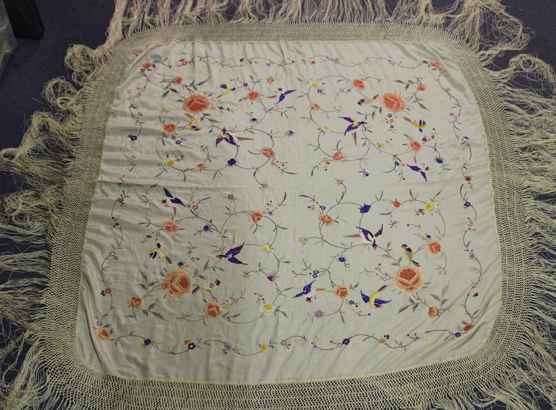 A Chinese cream silk shawl, early 20th Century, worked in coloured threads with birds flying amongst
