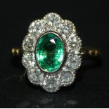A gold, emerald and diamond oval cluster ring, collet set with the oval cut emerald within a