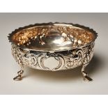 A Victorian silver circular sugar bowl with shaped rim, the sides chased with a flower and scroll