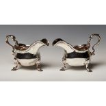A pair of George II silver sauce boats, each body engraved with an armorial beneath a gadrooned rim,