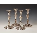 A set of four George II cast silver Rococo candlesticks, with detachable cast foliate scroll edged