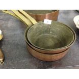 3 graduated copper pans with brass handles.