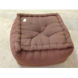 A brown upholstered foot stool.