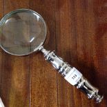 A magnifying glass with silver coloured handle