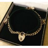 A heavy hallmarked silver charm bracelet with heart shaped 'padlock' clasp and safety chain.  With 3
