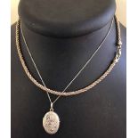 A white metal oval locket, engraved to front, on a silver chain together with a choker style, 2