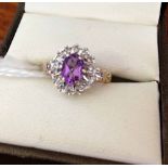 9ct gold ladies dress ring set with central oval amethyst surrounded by small diamonds. Size K.