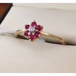 Ladies 9ct gold dress ring with flower design set with central diamond enclosed by garnets. Size