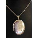 A large hallmarked silver oval engraved locket on 24" chain. Total weight approx 36.5g, locket